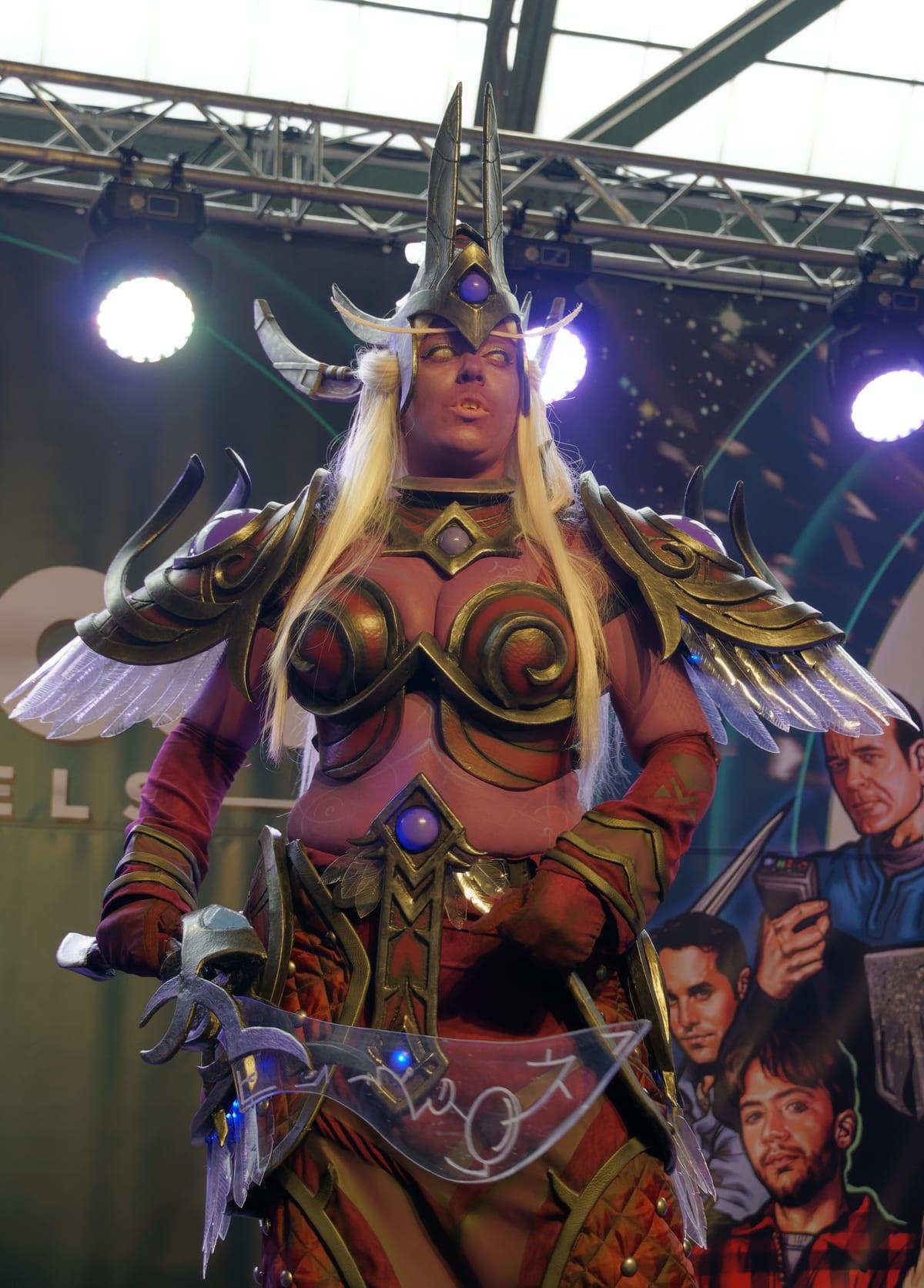 A cosplayer in ornate fantasy armour with layered shoulder pieces, patterned plates and a full-length costume