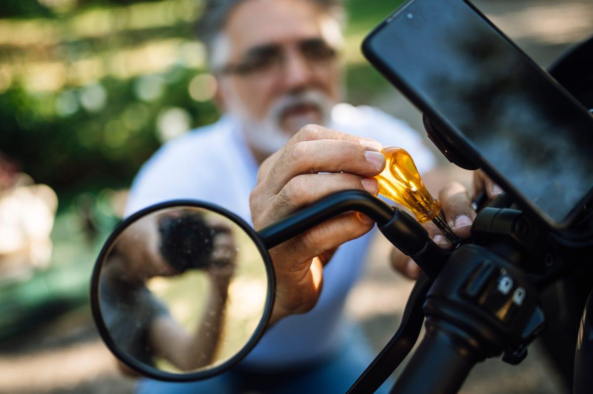 A man working on the handlebar assembly of a motorcycle with hand tools