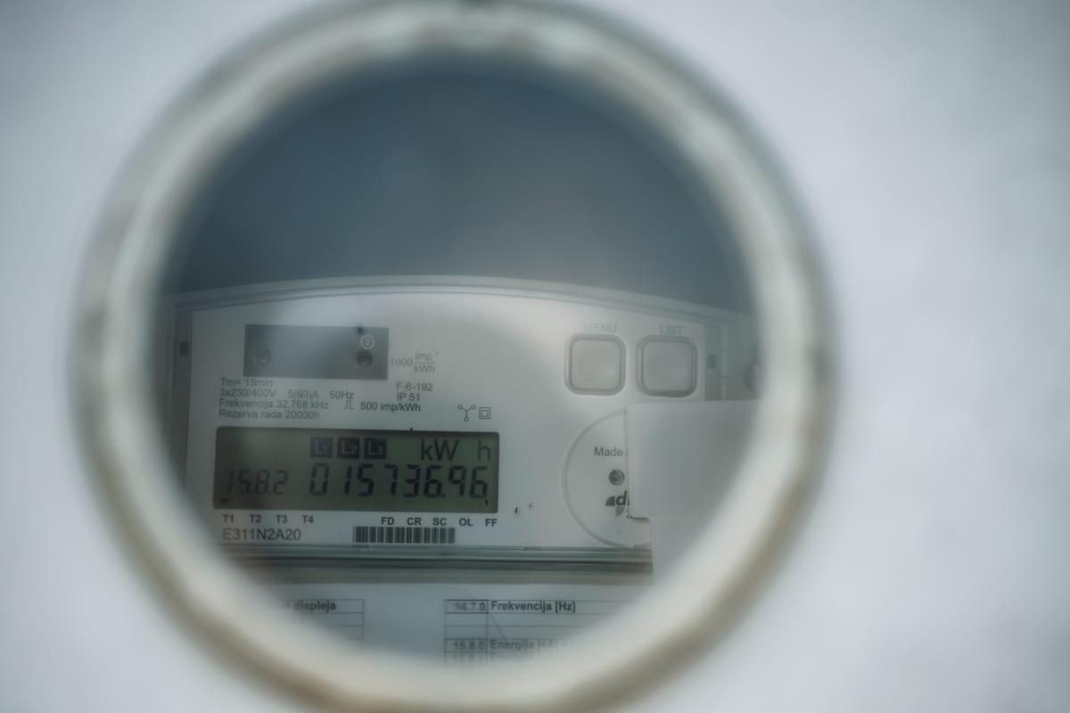Close-up through the round window of a residential electricity meter showing a digital display reading in kilowatt hours