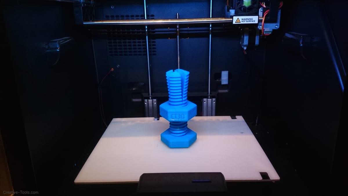A plastic bolt with a nut threaded onto it, both produced in a single 3D print