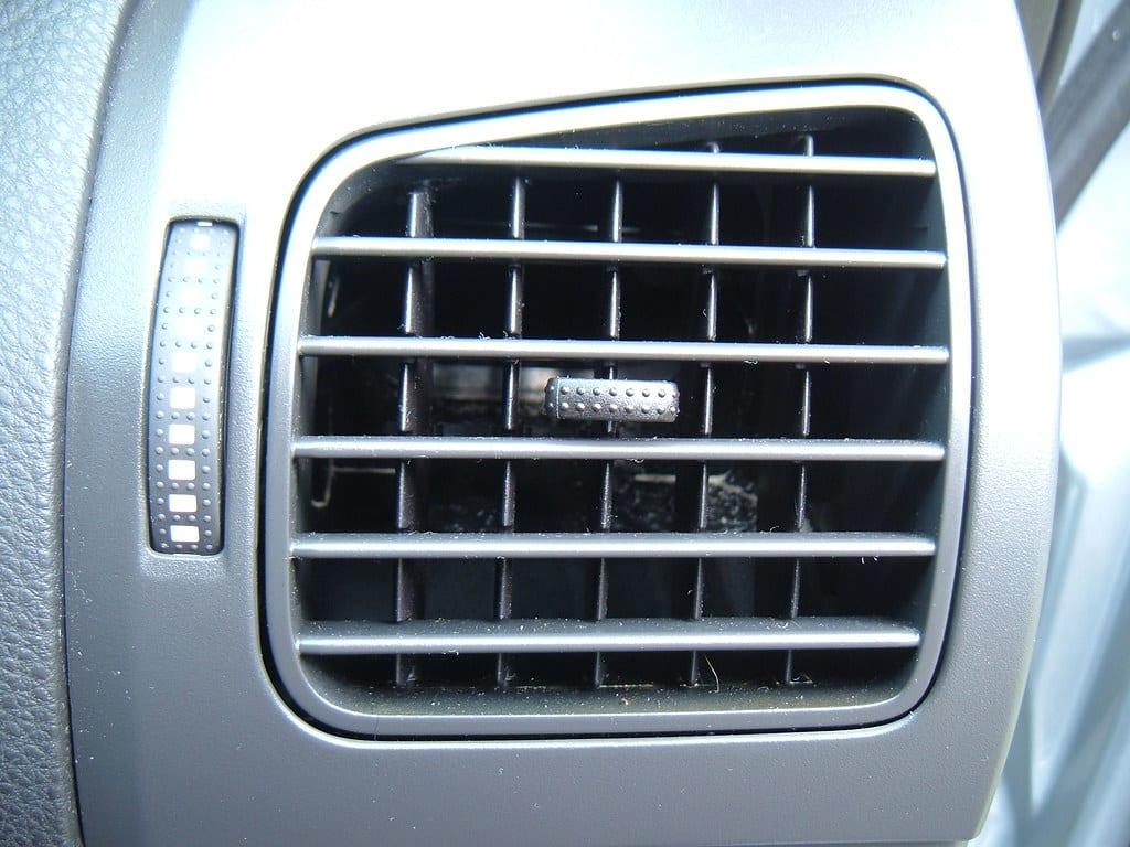 Close-up of a grey plastic dashboard air vent with louvre vanes and trim bezel