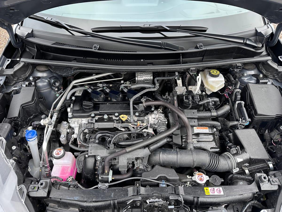 Engine bay of a modern hybrid hatchback with the bonnet open, showing plastic covers, hoses and brackets packed around the engine