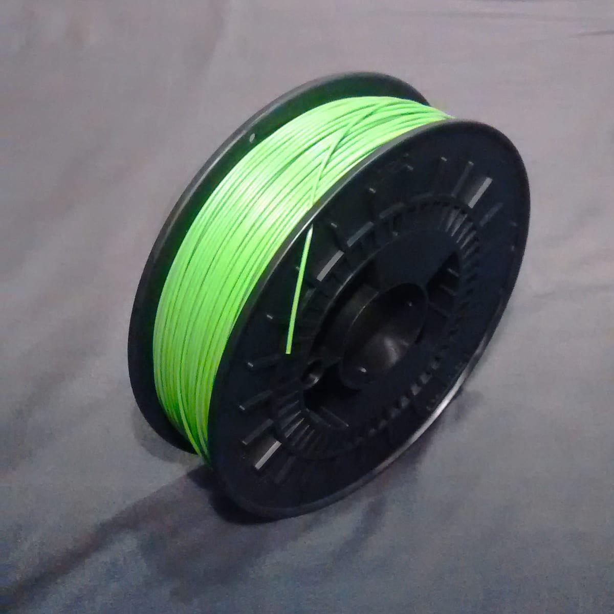 A spool of green ABS filament wound on a plastic reel
