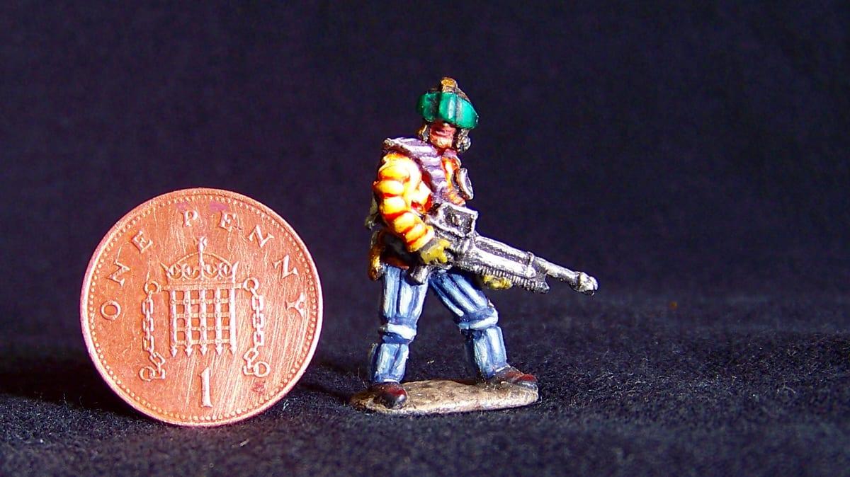A hand-painted miniature figure photographed beside a coin for scale