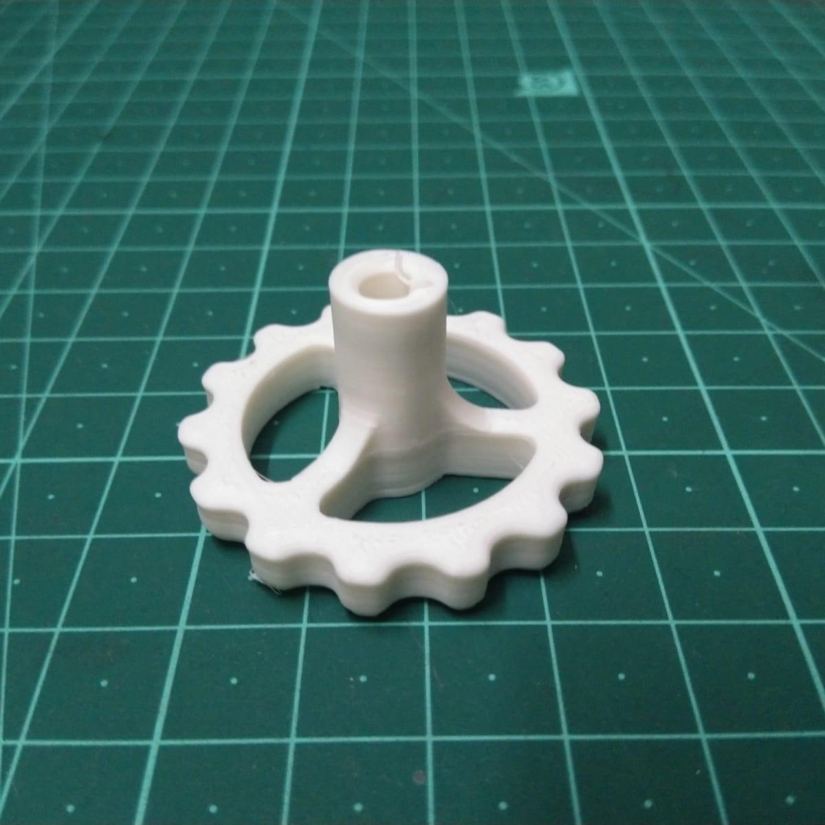 A white 3D printed control knob on a cutting mat, with a scalloped grip rim, an open central boss for the shaft and visible layer lines