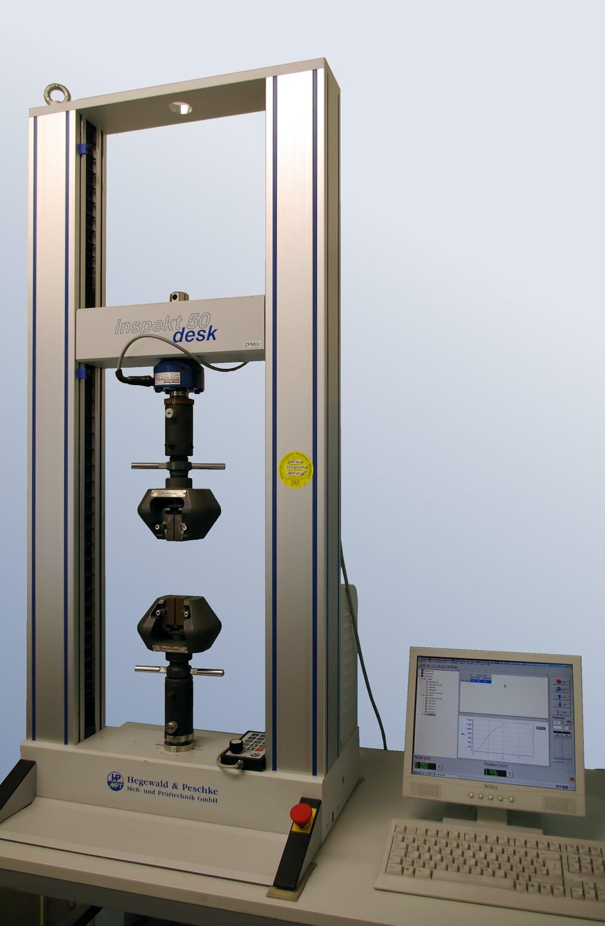 A benchtop universal testing machine with a load frame, crosshead and specimen grips