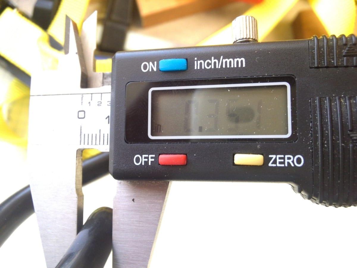 Digital calliper closed around a small part, with the millimetre and inch display visible